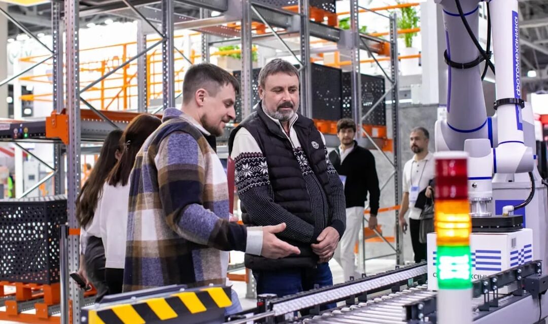 Men observe automated conveyor belt system in warehouse