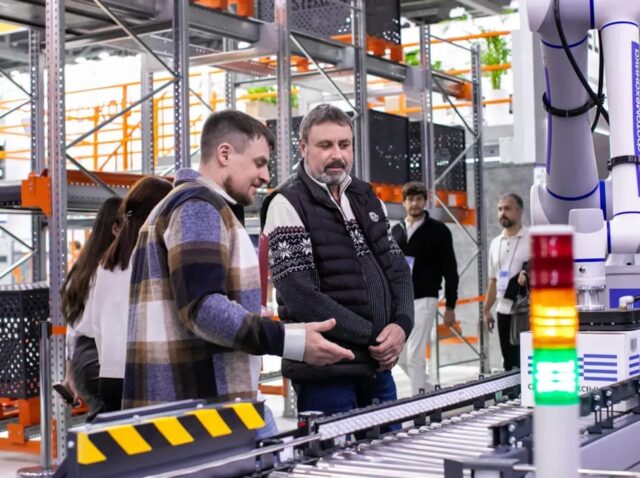 Men observe automated conveyor belt system in warehouse